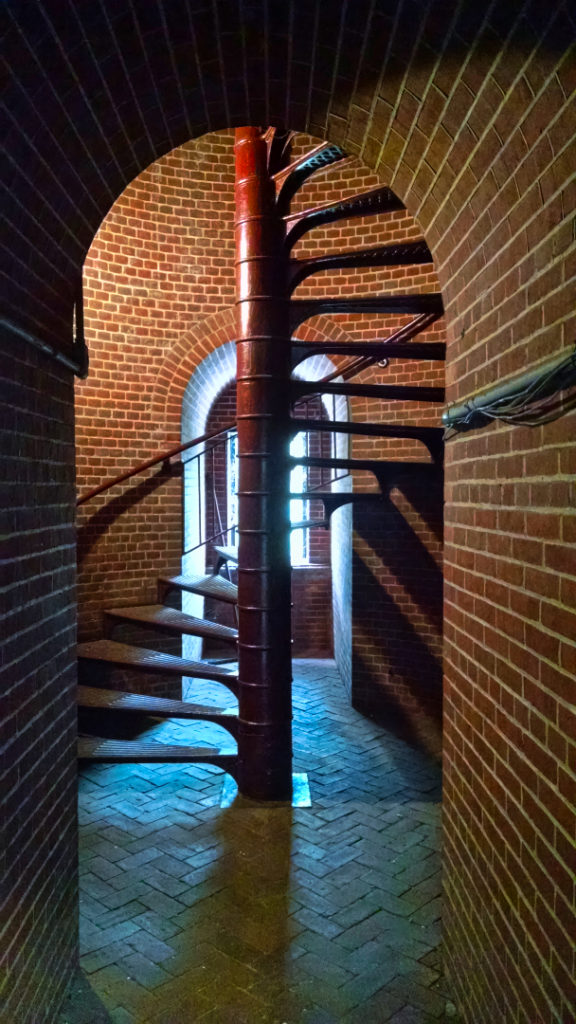 Interior view of the stairwell of the Assateague lighthouse casting shadows on the brick walls.